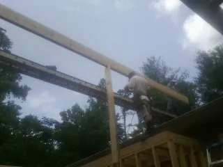 Carpenter setting a ridge beam over a new addition frame — Ice Dam Removal by Roofing Brothers in Trion