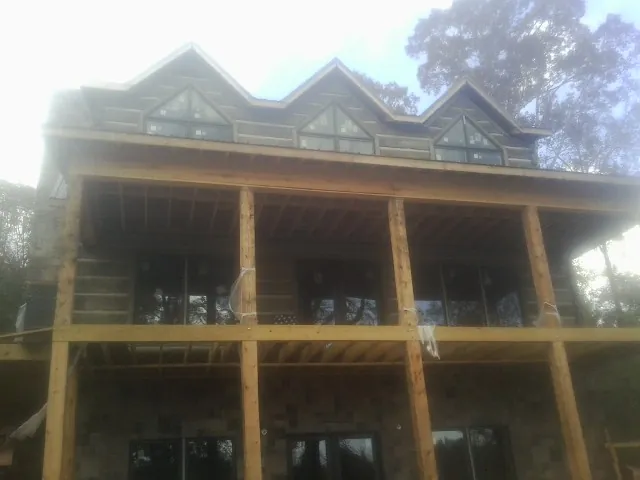 Dormers and porch framing on a large log home under construction — Roof Coating work by our crew in Trion