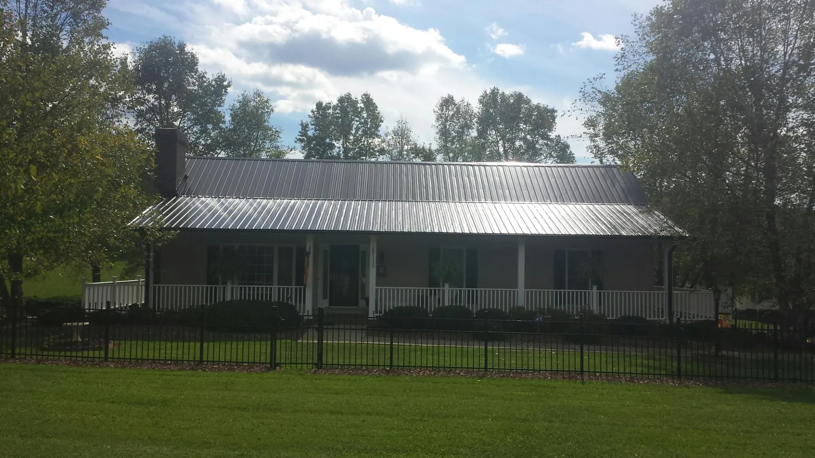 Gray metal roof on a brick ranch with a full width front porch in Trion