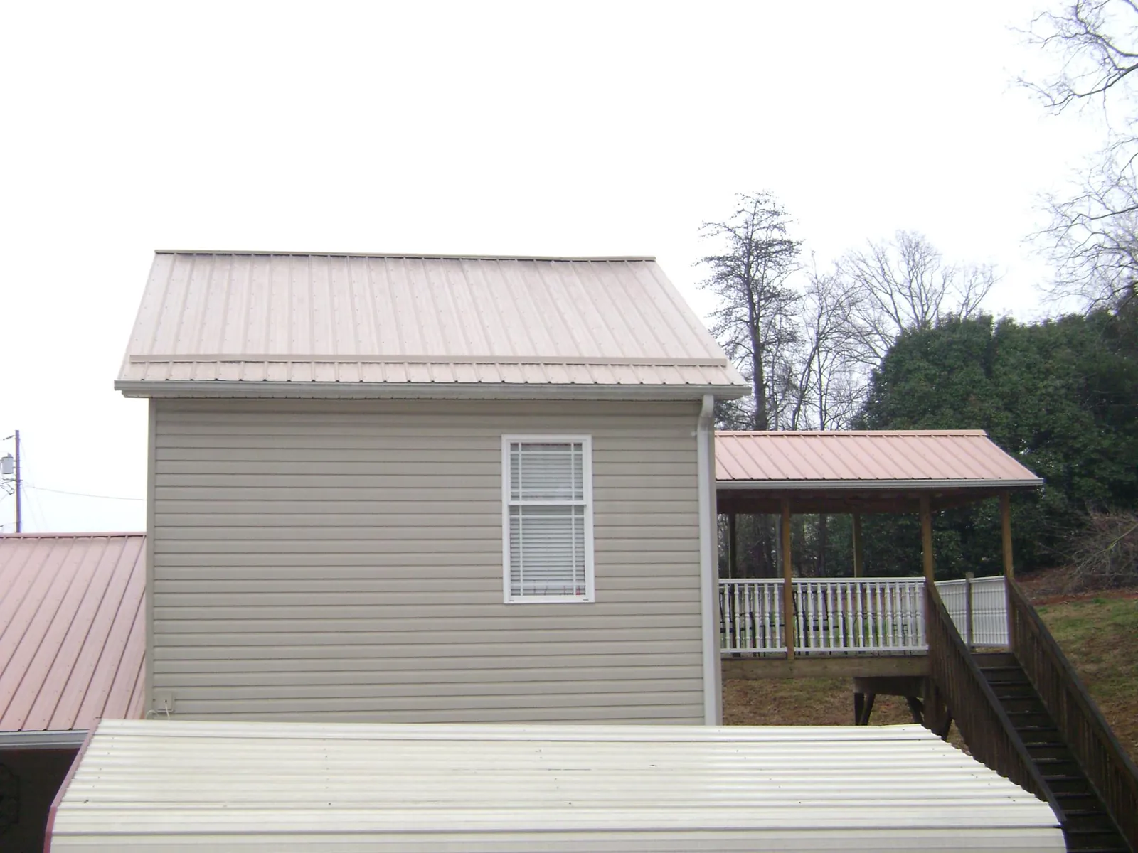 Tan metal roofs on a two story addition and attached porch, from a Roof Replacement job in Trion