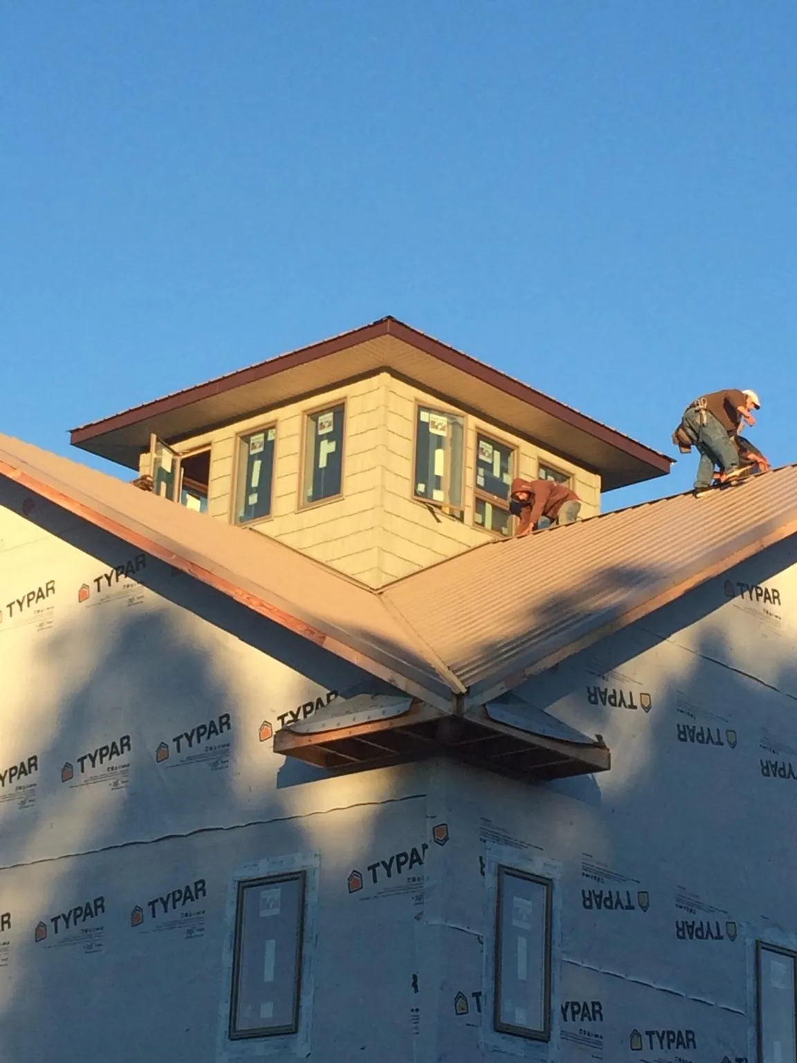 Roofers working around a rooftop cupola on a new metal roof at sunset — Roof Waterproofing in Trion by Roofing Brothers